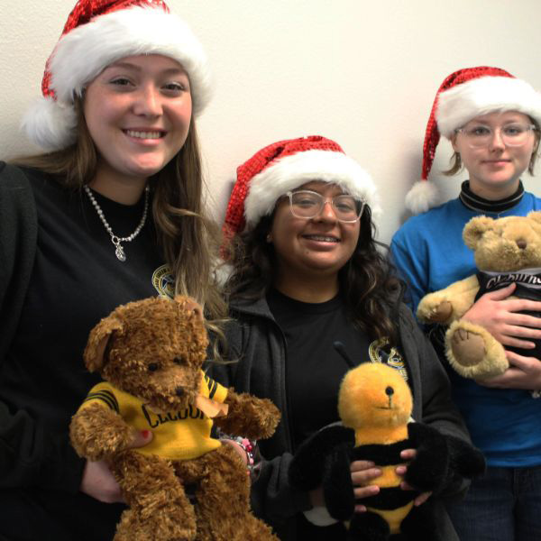  three girls in Santa hats holding stuffed animals